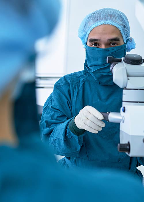 medizintechnik Ausschnitt eines Labors, in dem ein Mitarbeiter im Schutzanzug und Mundschutz am Mikroskop arbeitet. Symbolisch steht das für die awisto CRM Branchenlösung Medizintechnik auf Basis von Dynamics CE.