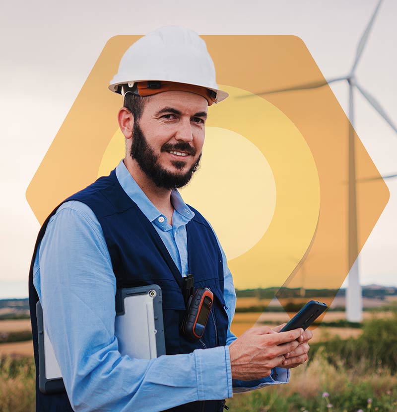 Das Bild zeigt einen Mitarbeiter vor Windrädern. Er nutzt Dynamics 365 Field Service auf dem Smartphone.