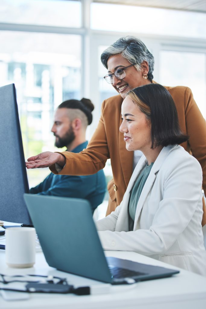 2 Mitarbeiter sitzen am Computer mit Schulungsdame im Büro für CRM